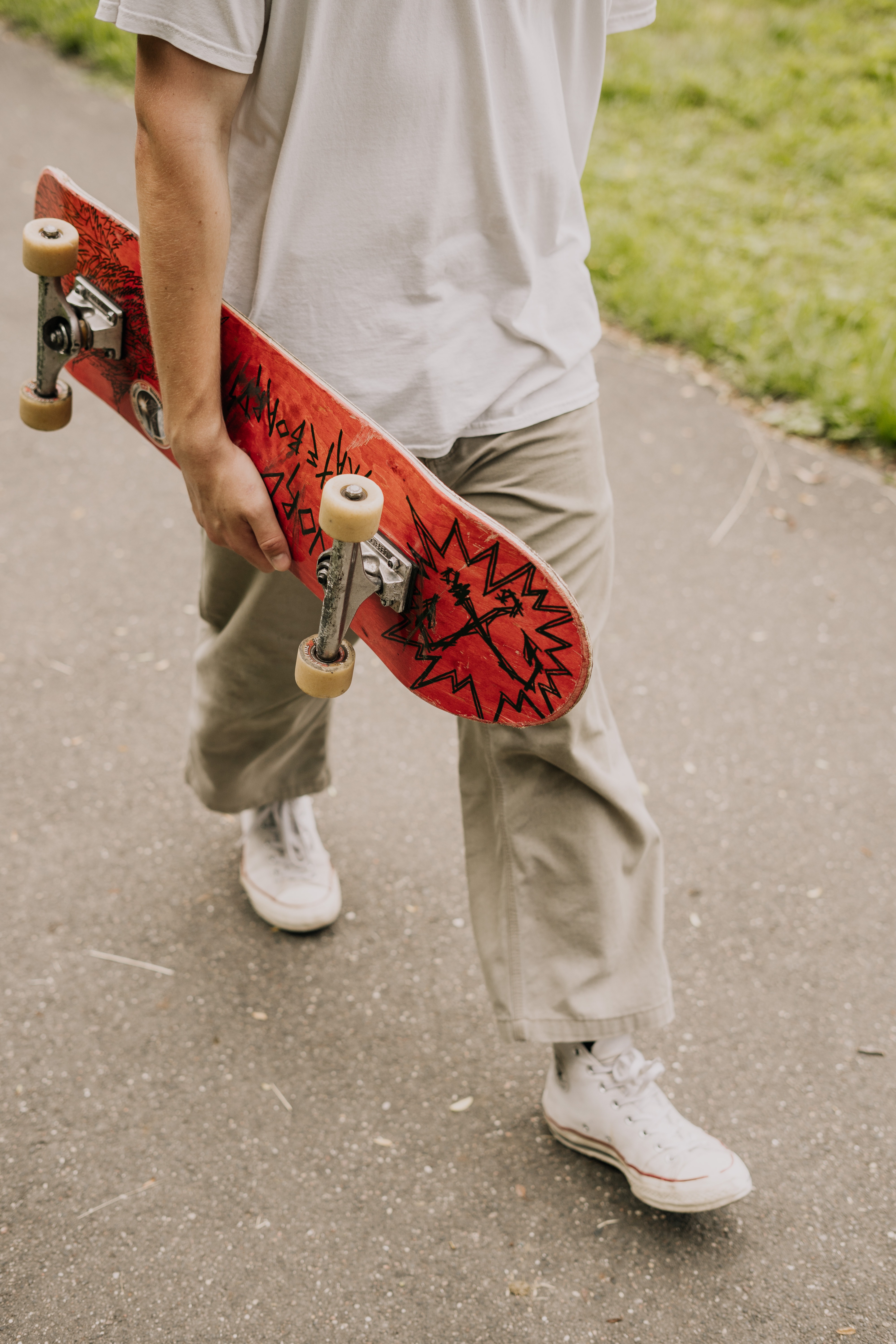 En der går med et rødt skateboard under armen