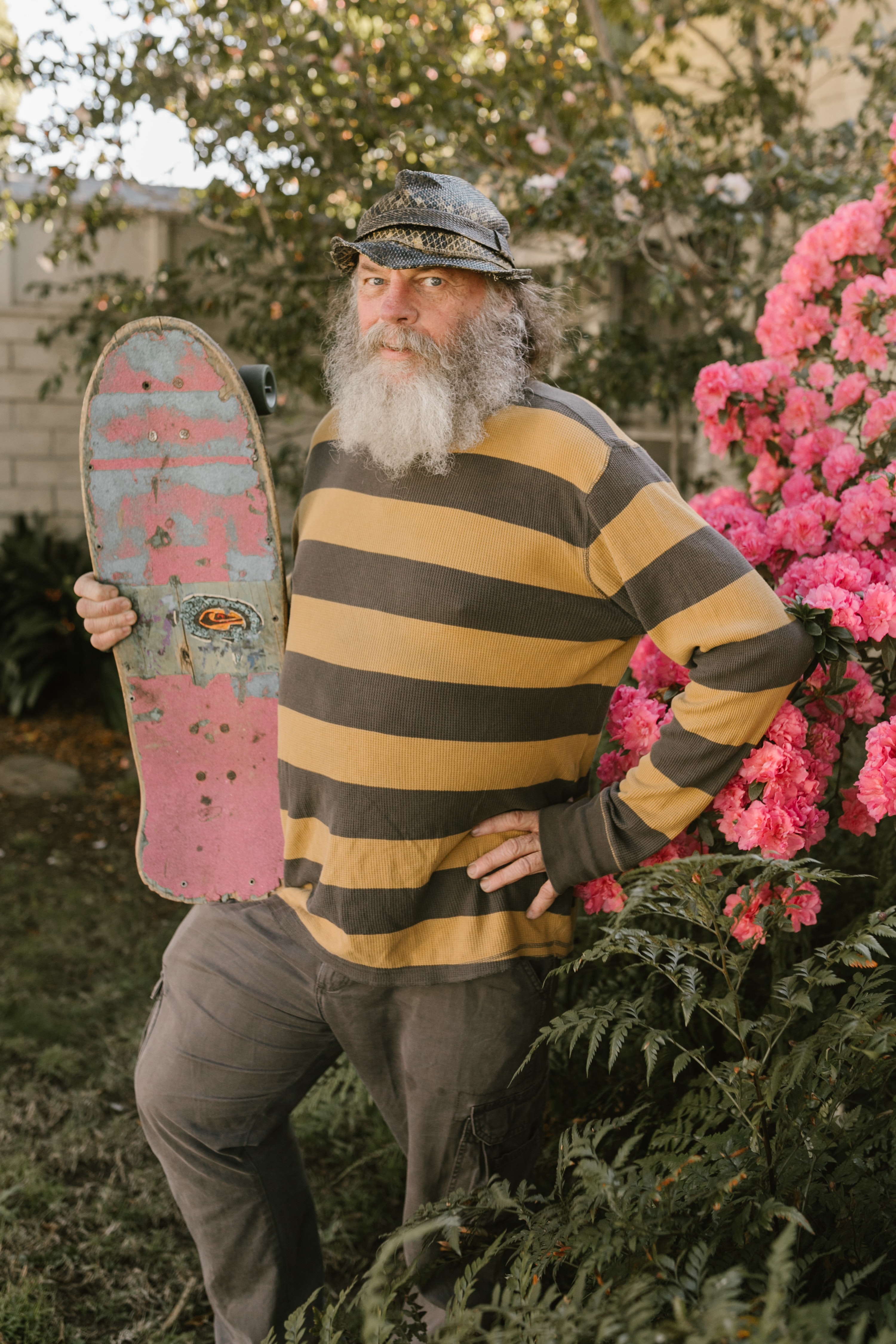 En ældre herre med et pink skateboard i højre hånd